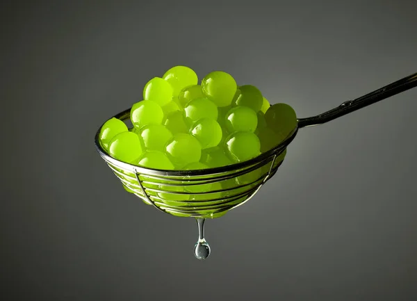 green jelly balls for making bubble tea in a strainer on grey background