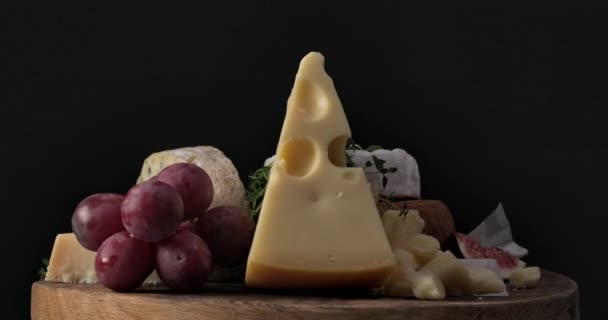 木制刨花板上的各种奶酪在黑色背景下旋转的静止生活 — 图库视频影像