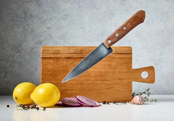wooden cutting board and levitating knife on grey background