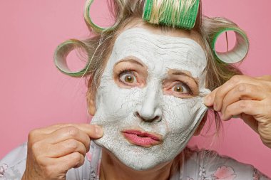 Killi maskeli, saç silindirli, cildini değiştirmek ve daha genç görünmek isteyen son sınıf öğrencilerinin portresi.