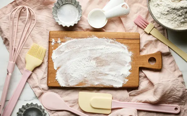various baking tools and flour on pink napkin, top view