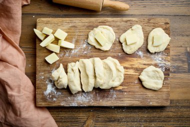 Ahşap mutfak masasında peynirle dolu hamur hamurlu çörekler.