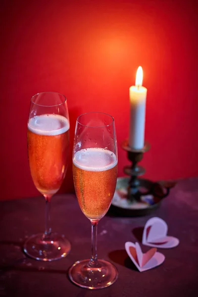 两杯香槟和红色背景上燃烧的蜡烛 — 图库照片