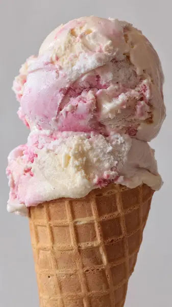 ライトグレーの背景にアイスクリームワッフルコーンとバニラストロベリー風味アイスクリームスクープのクローズアップ ストック写真