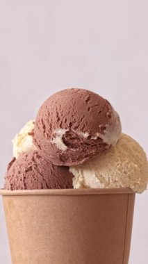 Çikolata ve vanilyalı dondurma kepçeleri, arka planda dönen bardakları alıp götürüyor. Tatlı tatlı, dönüşümlü yakın çekim. 4K 