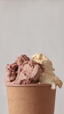 Kahverengi kağıt bardakta kavrulan vanilya ve çikolata aromalı dondurmayı kapat. Yaz tatlısı. Açık gri renk arkaplanı