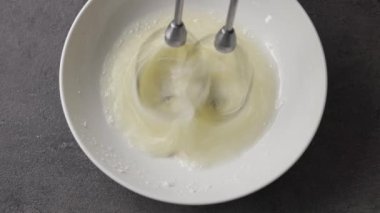 Şef çırpılmış yumurta beyazı ve pudra şekerini karıştırıcıyla karıştırır. Yiyeceklere yakın çekim