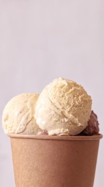 Çikolata ve vanilyalı dondurma kepçeleri, arka planda dönen bardakları alıp götürüyor. Tatlı tatlı, dönüşümlü yakın çekim. 4K 