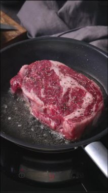 Bir şef mutfakta tavada biftek pişirir, yakın plan yemek. Lezzetli biftek yapma süreci.