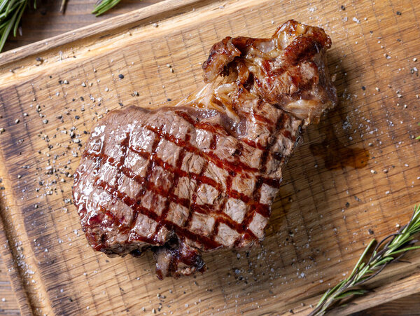 Freshly grilled steak on wooden cutting board, top view