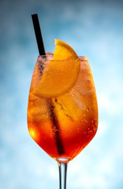 Mavi arka planda şarap kadehinde aperol spreyi kokteyli.