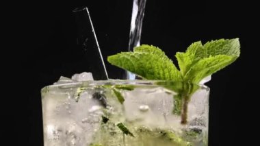 Mojito kokteyli hazırlama süreci. Buzlu bardağa köpüklü su dökmeye yakın. Buzlu buzlu mojito. Lezzetli limon ve nane likörü..