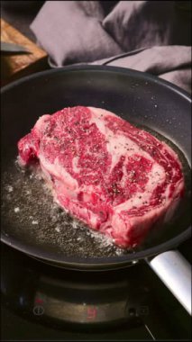 Bir şef mutfakta tavada biftek pişirir, yakın plan yemek. Lezzetli biftek yapma süreci.