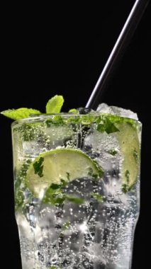 Mojito kokteyli hazırlama süreci. Buzlu bardağa köpüklü su dökmeye yakın. Buzlu buzlu mojito. Lezzetli limon ve nane likörü..