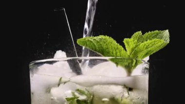 Mojito kokteyli hazırlama süreci. Buzlu bardağa köpüklü su dökmeye yakın. Buzlu buzlu mojito. Lezzetli limon ve nane likörü..