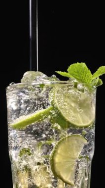 Mojito kokteyli hazırlama süreci. Buzlu bardağa köpüklü su dökmeye yakın. Buzlu buzlu mojito. Lezzetli limon ve nane likörü..