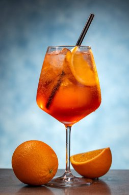 Mavi arka planda şarap kadehinde aperol spreyi kokteyli.