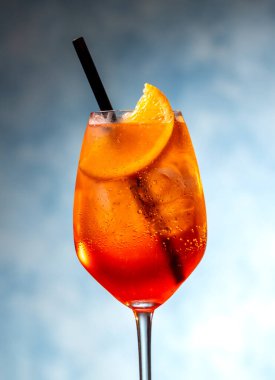 Mavi arka planda şarap kadehinde aperol spreyi kokteyli.