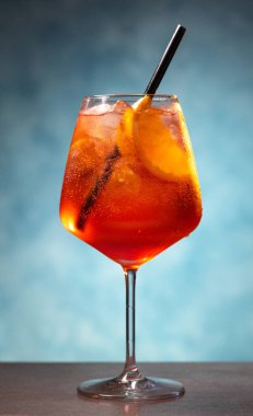 Mavi arka planda şarap kadehinde aperol spreyi kokteyli.