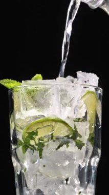 Mojito kokteyli hazırlama süreci. Buzlu bardağa köpüklü su dökmeye yakın. Buzlu buzlu mojito. Lezzetli limon ve nane likörü..