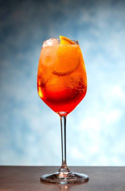 Mavi arka planda şarap kadehinde aperol spreyi kokteyli.