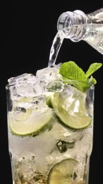 Mojito kokteyli hazırlama süreci. Buzlu bardağa köpüklü su dökmeye yakın. Buzlu buzlu mojito. Lezzetli limon ve nane likörü..