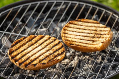 Bahçedeki kömür ızgarasında ızgara hamburger ekmeği.