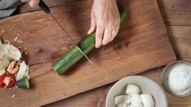 Şef taze bir salatalığı ahşap mutfak tahtasında bıçakla kesiyor. Sağlıklı bir akşam yemeği için. Gazpacho çorbası yapma süreci
