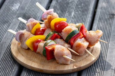 Taze çiğ tavuk eti ve ahşap kesme tahtasındaki sebze şişleri ızgara için hazır.