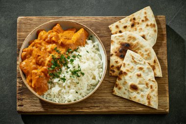 Bir kase tavuklu Tikka Masala pilav ve koyu gri Hint restoranı masasında düz ekmek.