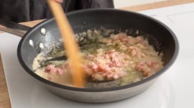 Aşçı mutfakta domuz pastırması ve erimiş tereyağını karıştırdı. Ev yapımı yemek yapma, evde yemek pişirme, yakın çekim.