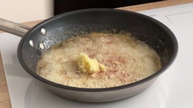 Aşçı mutfakta erimiş tereyağına rendelenmiş sarımsak ve pastırma koyar. Ev yapımı yemek yapma, evde yemek pişirme, yakın çekim.