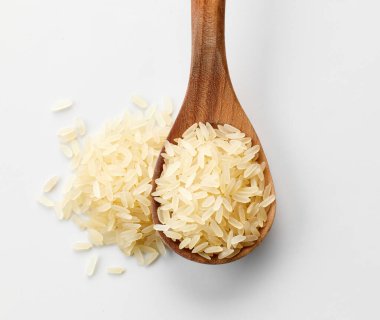 raw rice in wooden spoon on white background, top view clipart