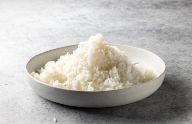 Gri mutfak masasında bir kase haşlanmış pirinç.