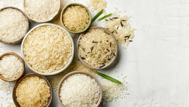 Beyaz mutfak masası yüzeyinde farklı pirinç türleri, üst görünüm