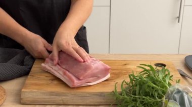 Aşçı, domuz pirzolası dilimini mutfaktaki tahta tahtada bıçakla kesmiş. Ev yapımı yemek yapma, evde yemek pişirme, yakın plan yemek, domuz rostosu pişirme.