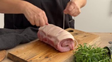 Mutfaktaki tahtanın üzerinde domuz pirzolası, ekmek kırıntısı, domuz pastırması ve tereyağı ile dolu iple temizlikçi kravatı. Ev yapımı yemek yapma, evde yemek pişirme, yakın plan yemek, domuz rostosu pişirme.