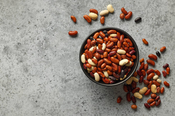 bowl of colorful raw beans on grey table, top view