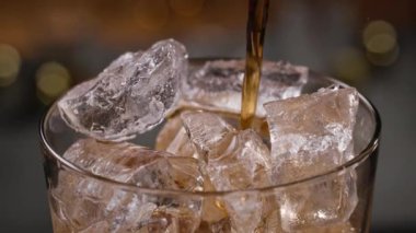 Buzlu bardağa dökülen taze kola, yaklaşın. Arka planda odaklı olmayan çubuk