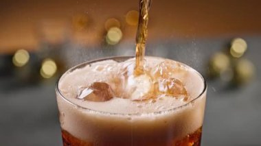 Buzlu bardağa dökülen taze kola, yaklaşın. Odaklanamayan şenlik arkaplanı