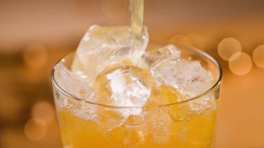 Taze portakal suyu bardakta buzlu, yakın çekim. Odaklanmamış turuncu şenlik arka planı