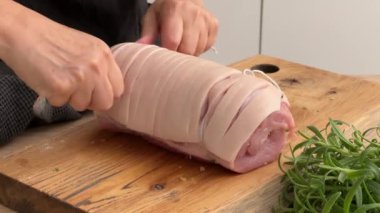 Mutfaktaki tahtanın üzerinde domuz pirzolası, ekmek kırıntısı, domuz pastırması ve tereyağı ile dolu iple temizlikçi kravatı. Ev yapımı yemek yapma, evde yemek pişirme, yakın plan yemek, domuz rostosu pişirme.