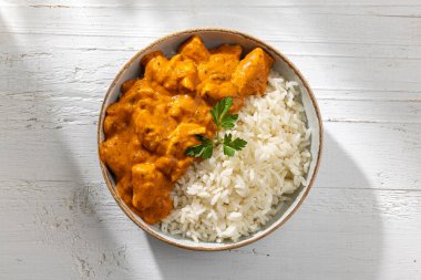 Beyaz ahşap mutfak masasında pilavlı tavuk Tikka Masala.