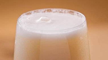 Sarı arka planda cam köpük yapan taze bira, ağır çekim.