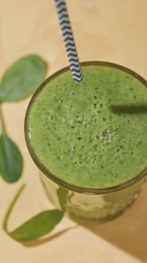 Bir bardak taze yapılmış yeşil ıspanak ve muzlu smoothie 'nin içine bir pipet koyar.