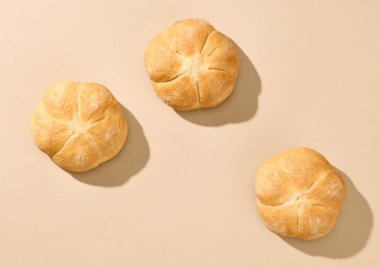 Bej arka planda taze pişmiş ekmek çörekleri, üst manzara.