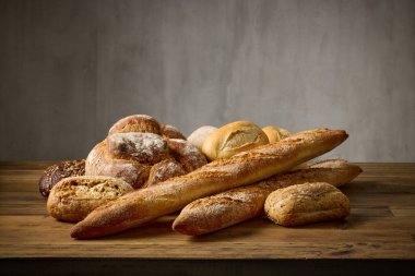 Fırındaki ahşap masa üzerinde çeşitli taze pişmiş ekmek çeşitleri