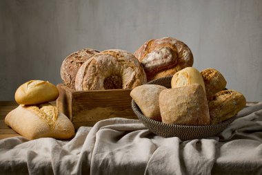 Fırındaki ahşap masa üzerinde çeşitli taze pişmiş ekmek çeşitleri