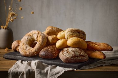 Fırındaki ahşap masa üzerinde çeşitli taze pişmiş ekmek çeşitleri