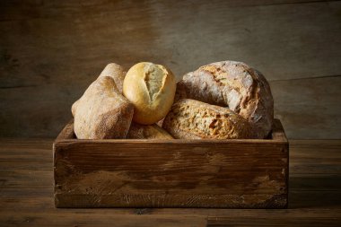 Fırındaki ahşap masa üzerinde çeşitli taze pişmiş ekmek çeşitleri